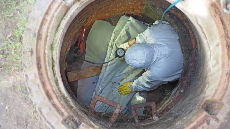 Technician performing tightness test on an industrial sewer pipeline with certified pressure measurement instrumentation